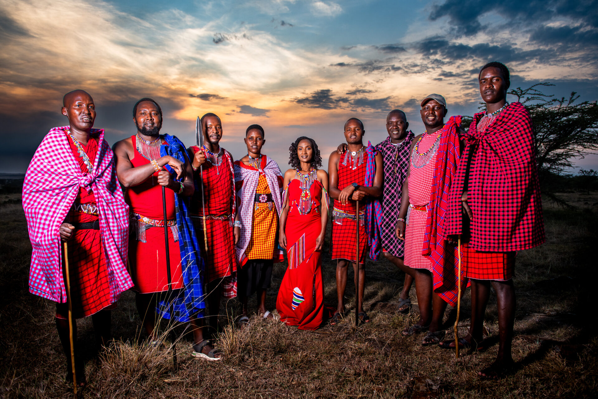 Group of Maasai performers standing together in traditional attire at dusk.