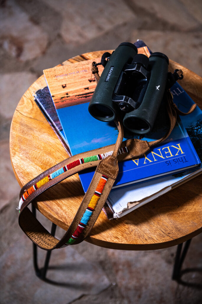 Safari binoculars, notebook and map on a wooden table at Kobe Mara camp in the Maasai Mara.